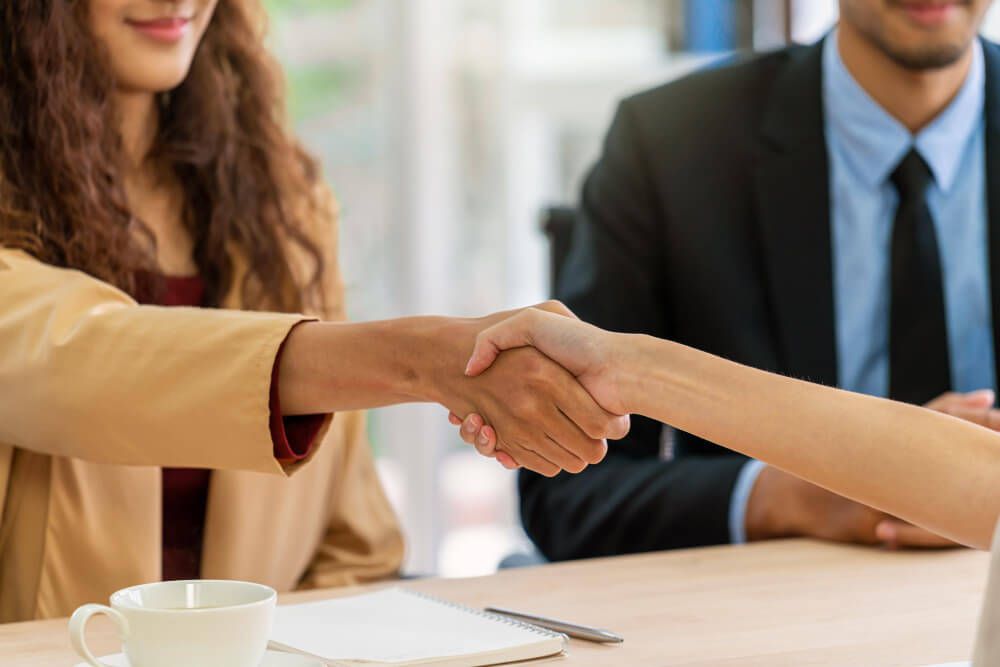 closeup-handshake-when-interview-between-young-asian-woman-and-two-manager (2) profissional de recursos humanos apertando a mão de uma candidata durante processo de entrevsta