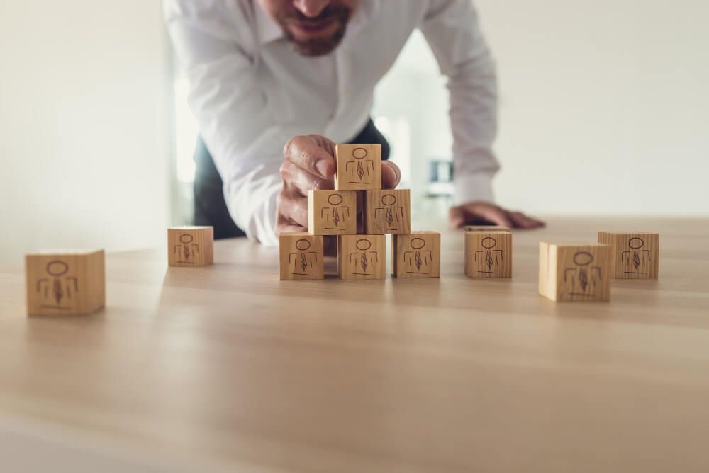business-executive-stacking-wooden-cubes-with-people-icons-on-office-desk (1) RH estratégico