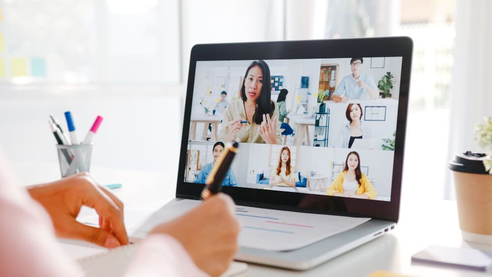 young-asia-businesswoman-using-laptop-talk-to-colleague-about-plan-in-video-call-meeting-while-work-from-home-at-living-room (1) dinâmicas de grupo online